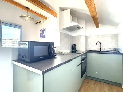 a kitchen with a microwave and a tv on a counter at Appartement 3 chambres à proximité des plages in Cannes