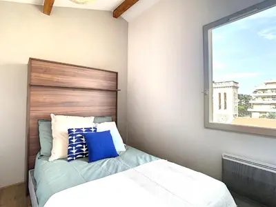a bedroom with a bed with a wooden headboard and a window at Appartement 3 chambres à proximité des plages in Cannes