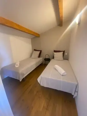 two beds in a small room with wooden floors at Appartement 3 chambres à proximité des plages in Cannes