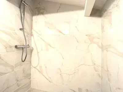 a shower in a bathroom with a white marble wall at Appartement 3 chambres à proximité des plages in Cannes