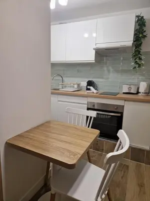 a kitchen with a wooden table and white cabinets at Studio cosy près de la Croisette in Cannes