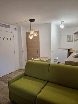 a living room with a green couch and a kitchen at Studio cosy près de la Croisette in Cannes