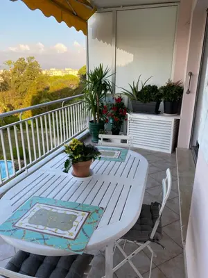 a white table and chairs on a balcony with plants at Les Pervenches in Cannes