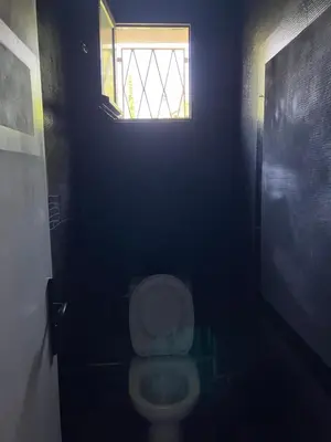 a bathroom with a toilet in a dark room with a window at Rez de Jardin Paisible avec Parking - Entrée des Artistes in Cannes