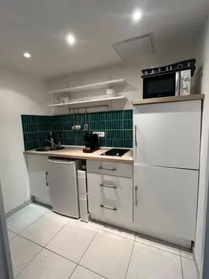 a small kitchen with white appliances and green tiles at Studio au cœur de Cannes in Cannes