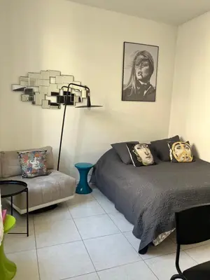 a bedroom with a bed and a couch and a lamp at Studio au cœur de Cannes in Cannes