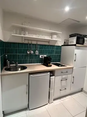 a kitchen with white cabinets and a sink and green tiles at Studio au cœur de Cannes in Cannes