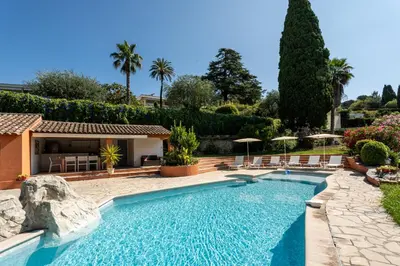 a pool in a yard with chairs and umbrellas at Dream Villa 300m2 & stunning 4000m2 private garden in Cannes