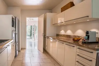 a kitchen with white cabinets and a tile floor at Dream Villa 300m2 & stunning 4000m2 private garden in Cannes