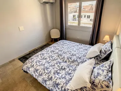 a bedroom with a bed with a blue comforter and a window at 1 bedroom rue d'Antibes , 1 min from the Croisette, 5 mins from the Palais 202 in Cannes