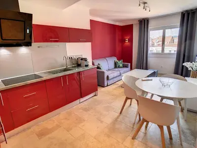 a kitchen and dining room with red cabinets and a table at 1 bedroom rue d'Antibes , 1 min from the Croisette, 5 mins from the Palais 202 in Cannes