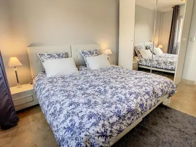 a bedroom with a blue and white bed and a mirror at 1 bedroom rue d'Antibes , 1 min from the Croisette, 5 mins from the Palais 202 in Cannes