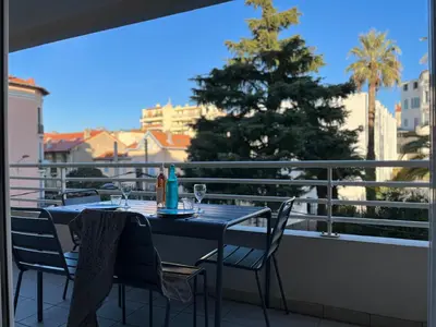a table and chairs on a balcony with a tree at Alice in Cannes