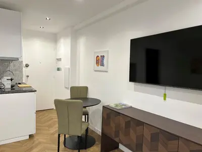 a living room with a table and a television on a wall at Moderne Studio BALCON, rue D'ANTIBES- HYPER CENTRE A0B191 in Cannes