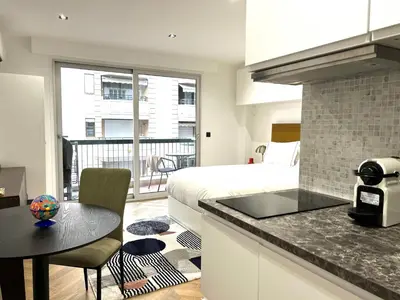 a bedroom with a bed and a kitchen with a table at Moderne Studio BALCON, rue D'ANTIBES- HYPER CENTRE A0B191 in Cannes
