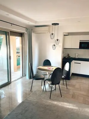 a living room with a table and chairs and a kitchen at 2 bedroom apartament close to the beach in Cannes