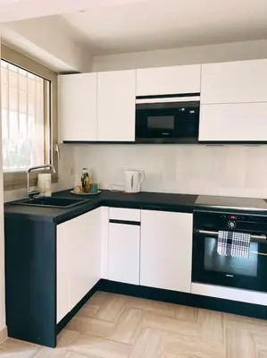 a kitchen with white cabinets and a black counter top at 2 bedroom apartament close to the beach in Cannes