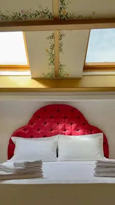 a bed with a red headboard and a window at L'échelle Rouge in Cannes