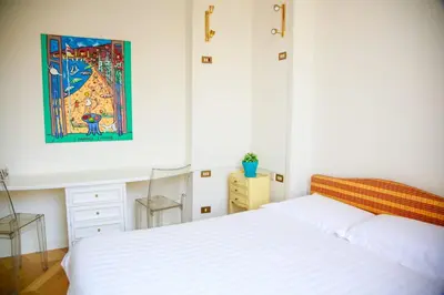 a bedroom with a white bed and a painting on the wall at L'échelle Rouge in Cannes