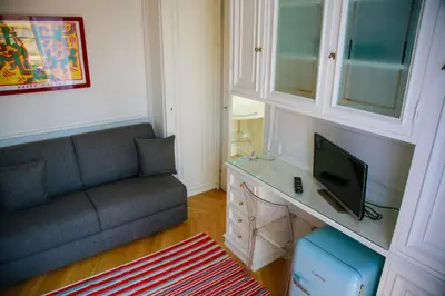 a living room with a couch and a desk with a television at L'échelle Rouge in Cannes