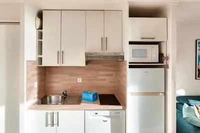 a small kitchen with white cabinets and a sink at Résidence Cannes Verrerie - maeva Home - Appartement climatisé 3 pièces 4 personnes - Budget MAE-6894 in Cannes