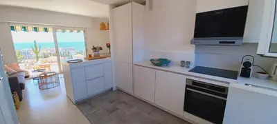 a kitchen with white cabinets and a tv on the wall at Vue mer à couper le souffle - nouveau entièrement rénové in Cannes