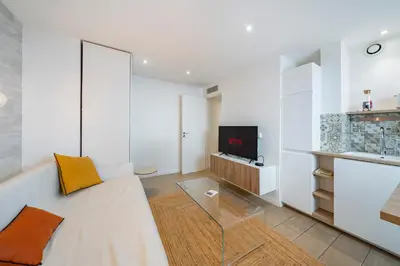 a living room with a white couch and a tv at Centre - 10mn Palais - Plages - Croisette - AT in Cannes