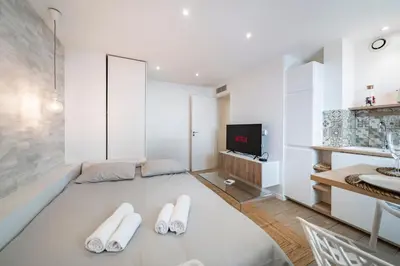 a living room with white furniture and a tv at Centre - 10mn Palais - Plages - Croisette - AT in Cannes