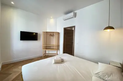 a white bedroom with a bed and a tv at New apartment in Forville with balcony in Cannes