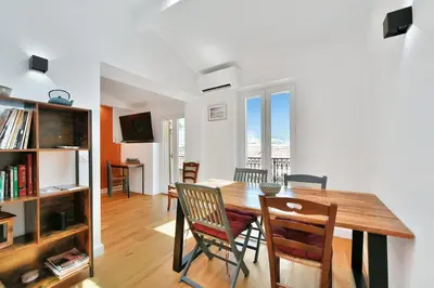 a dining room and living room with a table and chairs at LE CHARMANT sublime Maison de Ville dans le Suquet au calme in Cannes