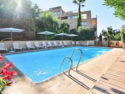 a swimming pool with white chairs and umbrellas at 2 pièces climatisé dans résidence avec piscine in Cannes