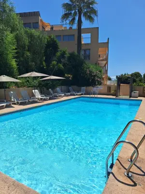 a large blue swimming pool with chairs and umbrellas at 2 pièces climatisé dans résidence avec piscine in Cannes