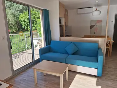 a living room with a blue couch and a balcony at 2 pièces climatisé dans résidence avec piscine in Cannes