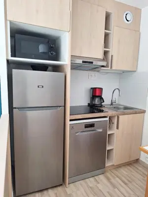 a small kitchen with a stainless steel refrigerator at 2 pièces climatisé dans résidence avec piscine in Cannes