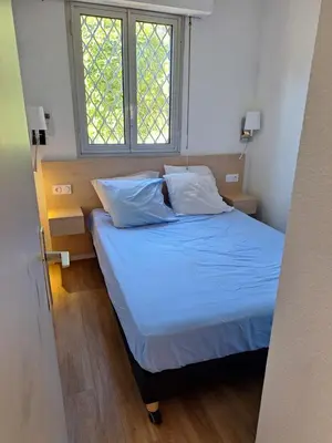 a bedroom with a bed with blue sheets and a window at 2 pièces climatisé dans résidence avec piscine in Cannes