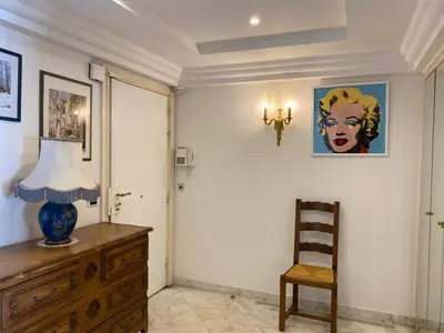 a room with a dresser and a lamp and a chair at Appartement Miramar Cannes Croisette in Cannes