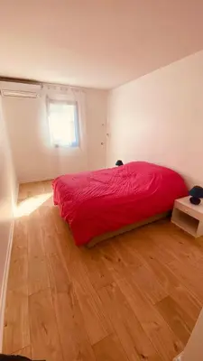 a bedroom with a red bed and a wooden floor at Cosy 3pièces à 5min de la plage in Cannes