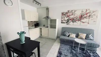 a living room with a couch and a table and a kitchen at Cosy 3pièces à 5min de la plage in Cannes