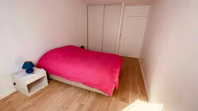 a small bedroom with a pink bed and a night stand at Cosy 3pièces à 5min de la plage in Cannes