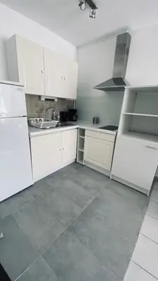 a white kitchen with white cabinets and a tile floor at Cosy 3pièces à 5min de la plage in Cannes