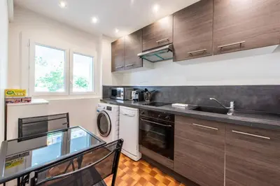 a kitchen with wooden cabinets and a sink and a dishwasher at Cannes Branly :2BDR Apartment in Cannes