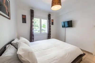a bedroom with a white bed and a television at Cannes Branly :2BDR Apartment in Cannes