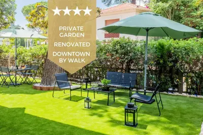 a lawn with chairs and an umbrella and a sign at Garden-level apartment 10-min on foot to City Center in Cannes