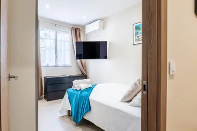a bedroom with a bed and a tv on the wall at Garden-level apartment 10-min on foot to City Center in Cannes
