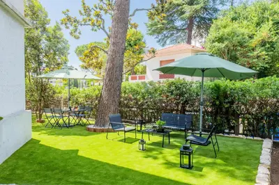 a lawn with chairs and an umbrella and a table at Garden-level apartment 10-min on foot to City Center in Cannes