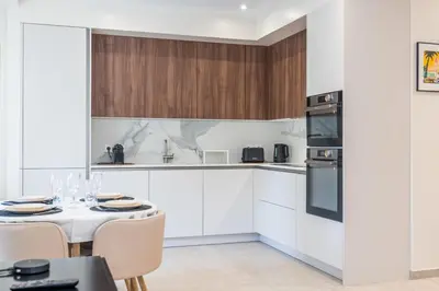 a kitchen with white cabinets and a table and chairs at Garden-level apartment 10-min on foot to City Center in Cannes