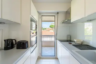 a kitchen with white cabinets and a view of a balcony at Lovely cosy nest close to the centre of Cannes in Cannes