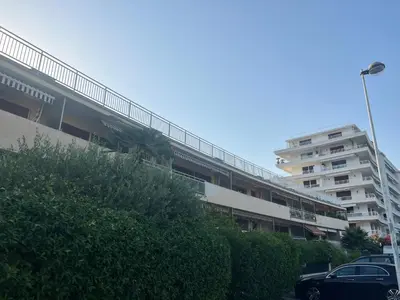 an apartment building with cars parked in a parking lot at Copacabana beach, by Welcome to Cannes in Cannes