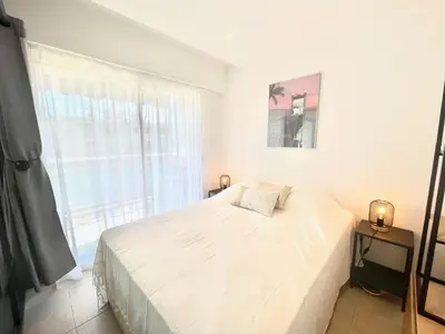 a white bedroom with a bed and a window at Copacabana beach, by Welcome to Cannes in Cannes