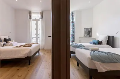 a bedroom with two beds and a door to a room at L'Elégance Rue d'Antibes - Palais & Plages - 200 m Croisette - Parking privé - Clim - Wifi in Cannes
